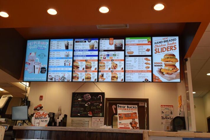 Digital menu boards behind restaurant counter